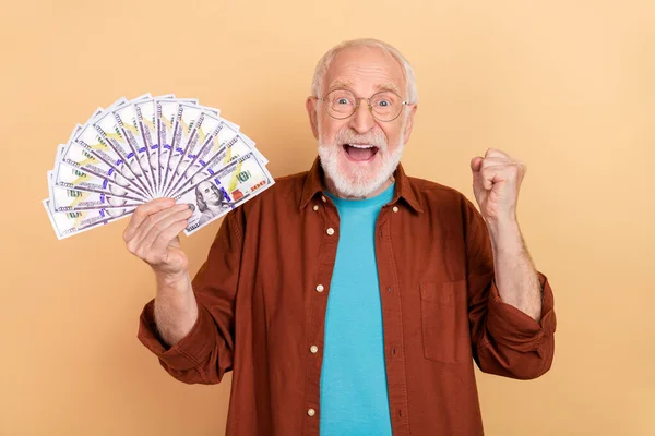 Heyecanlı, sevinçli, çığlık atan emeklinin fotoğrafı. Başarılı bir emeklinin yumruğunu kaldır. Bej rengi arka planda izole edilmiş para kazan. — Stok fotoğraf