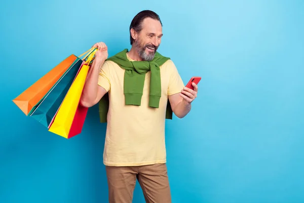 Retrato de persona excitada divertida uso teléfono leer mantenga paquetes aislados sobre fondo de color azul — Foto de Stock