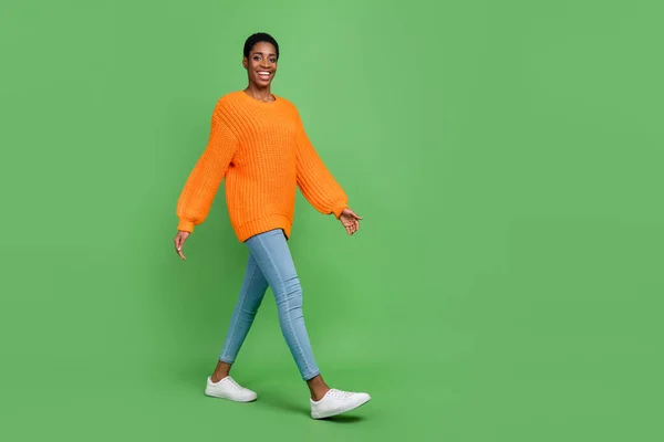 Pełna długość zdjęcie słodkie millenium brunet facet iść nosić sweter dżinsy obuwie izolowane na zielonym tle — Zdjęcie stockowe