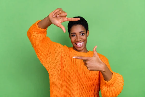 Foto av funky millennial brunett dam göra foto slitage orange pullover isolerad på grön färg bakgrund — Stockfoto