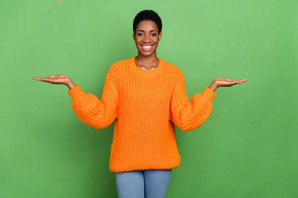 Zdjęcie ładne młoda brunetka pani trzymać ręce nosić pomarańczowy sweter izolowany na zielonym tle kolor — Zdjęcie stockowe