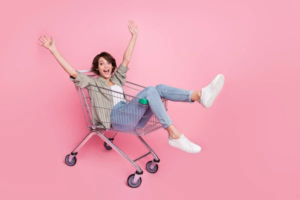 Retrato em tamanho completo de senhora positiva surpreso sentar no carrinho levantar as mãos se divertir isolado no fundo cor-de-rosa — Fotografia de Stock