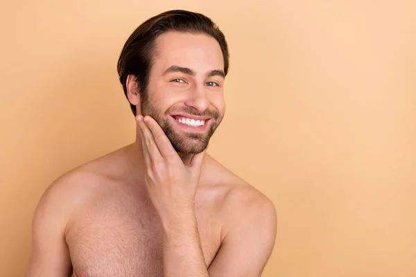 Photo de jeune homme joyeux main toucher barbe choyer gel hydratant isolé sur fond de couleur beige — Photo