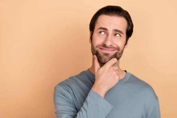 Foto de un hombre joven mano tacto barbilla mirada interesada espacio vacío pensar mente inseguro aislado sobre fondo de color beige —  Fotos de Stock