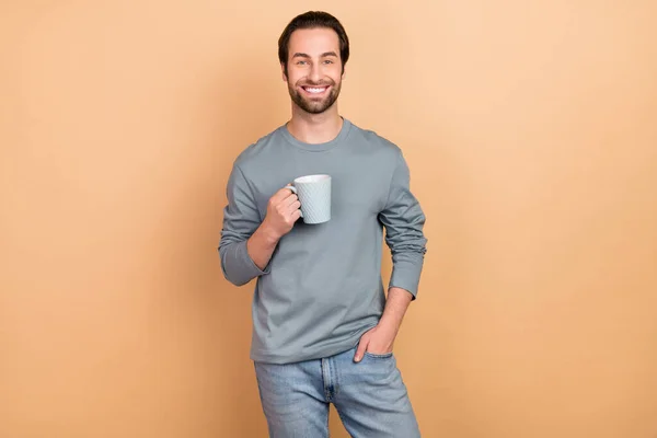 Foto do jovem gosta de bebida matinal saborosa cappuccino café expresso cafeína isolada sobre fundo de cor bege — Fotografia de Stock