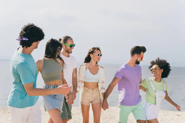Retrato de pessoas positivas alegres andar segurar braços desfrutar pendurado à beira-mar praia de areia ao ar livre — Fotografia de Stock
