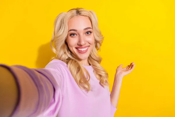 Neşeli şirin kızın fotoğrafı, selfie kolu palmiyesini sarı arkaplanda izole edilmiş boş bir alan göstermesine neden olur. — Stok fotoğraf