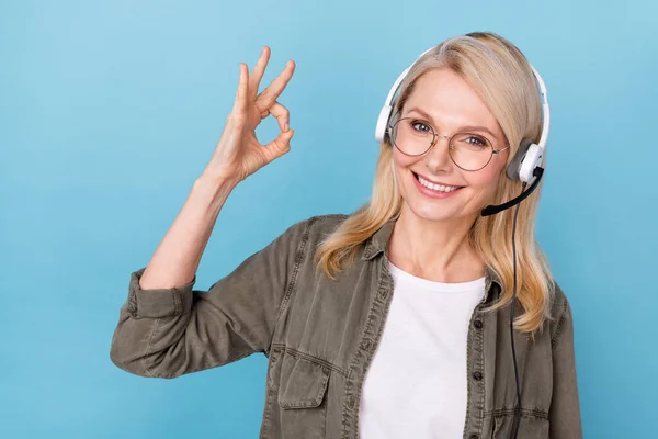 Photo of consultant middle aged lady make okay symbol help line use headphones mic isolated blue color background — Stock Photo, Image