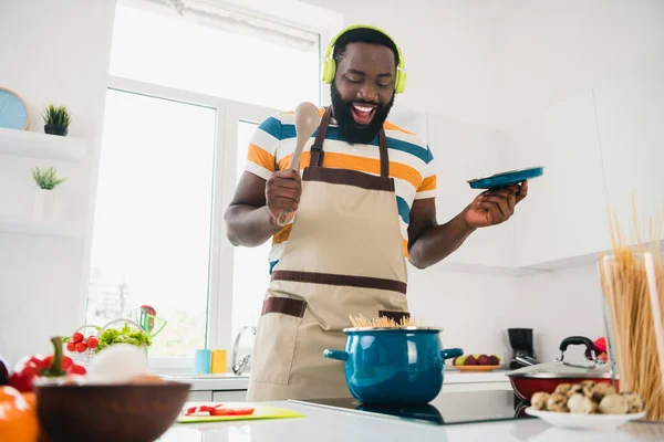 Портрет смішного веселого красивого хлопця насолоджується приготуванням смачної пасти слухати музику mp3 кухня в приміщенні — стокове фото