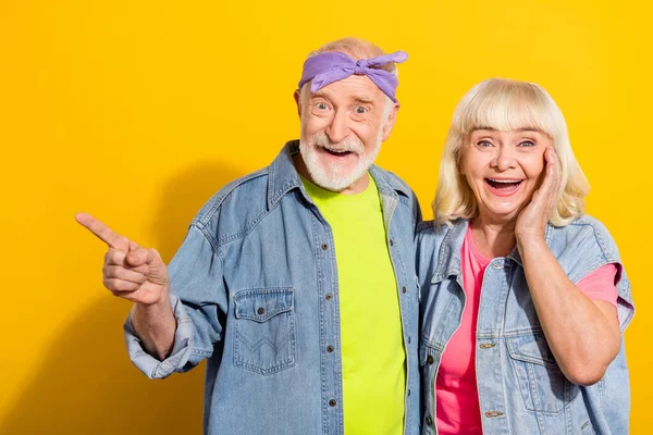 Foto de marido jubilado emocionado esposa usar jeans ropa que muestra el espacio vacío aislado de color amarillo de fondo —  Fotos de Stock