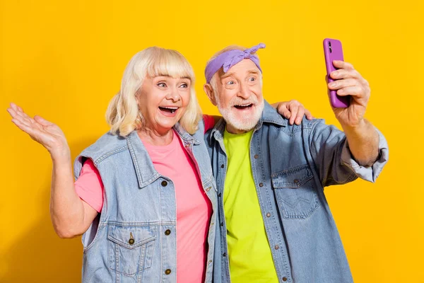 Foto van mooie vriend vriendin gepensioneerde gekleed denim outfit comminicating moderne gadget geïsoleerde gele kleur achtergrond — Stockfoto