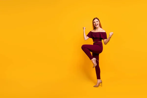 Full length φωτογραφία του ενθουσιασμένοι γοητευτικό νεαρή κοπέλα ντυμένος κόκκινα ρούχα περπάτημα κενό χώρο αυξάνεται γροθιές απομονωμένο κίτρινο χρώμα φόντο — Φωτογραφία Αρχείου