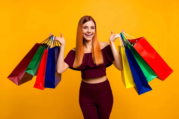 Çekici bir kadının fotoğrafı kırmızı elbise giyer yükselen alışveriş alışverişleri izole edilmiş sarı renk arka plan — Stok fotoğraf