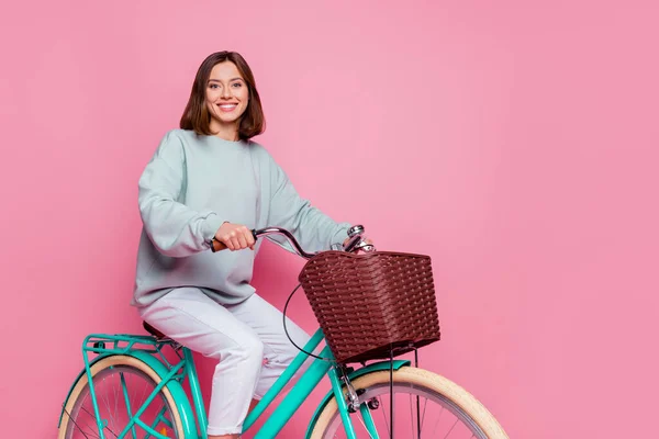 Profiel zijkant foto van jong vrij vrolijk meisje genieten paardrijden fiets geïsoleerd over roze kleur achtergrond — Stockfoto