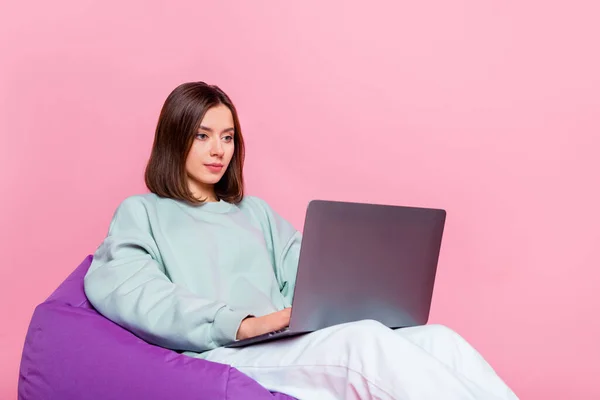 Foto de bonito peinado bob joven dama sentarse escribir portátil usar pantalones con capucha aislado sobre fondo rosa — Foto de Stock