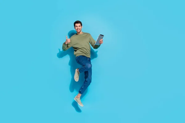 Corpo inteiro foto de hooray jovem morena cara salto segurar tablet polegar para cima desgaste camisa jeans tênis isolado no fundo azul — Fotografia de Stock