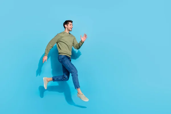 Foto de comprimento total de bonito millennial morena cara executar desgaste camisa jeans tênis isolado no fundo azul — Fotografia de Stock