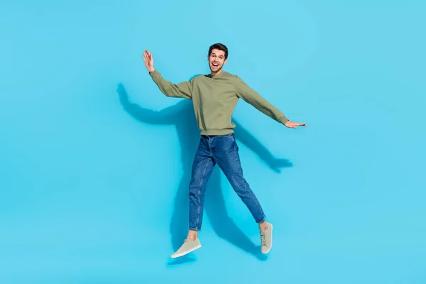 Retrato de corpo inteiro de satisfeito feliz jovem desfrutar de salto de tempo livre isolado no fundo de cor azul — Fotografia de Stock