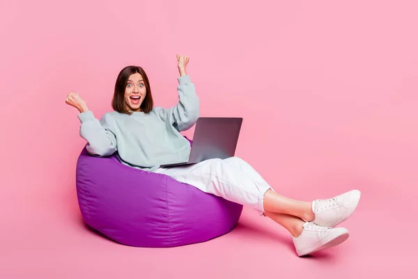 Foto ukuran penuh dari bob gaya rambut wanita Milenial duduk memegang laptop memakai sepatu celana hoodie terisolasi di latar belakang merah muda — Stok Foto