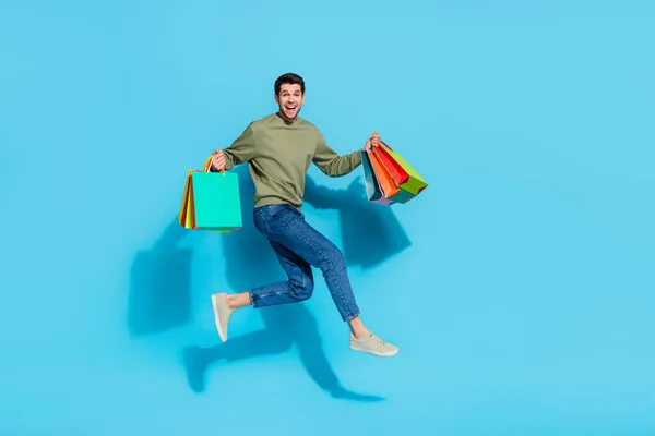 Foto de tamaño completo de chico guapo loco prisa paquetes de retención de prisa saltar aislado sobre fondo de color azul — Foto de Stock