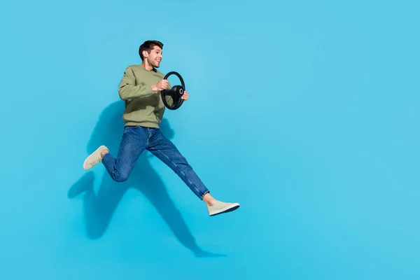 Full size foto van grappige duizendjarige brunet jongen rijden auto kijken promo wear shirt jeans schoenen geïsoleerd op blauwe achtergrond — Stockfoto