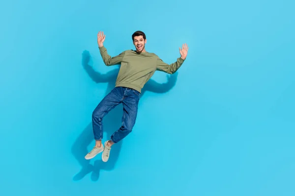 Full size φωτογραφία του εντυπωσιασμένος νεαρός brunet τύπος άλμα φορούν πουκάμισο τζιν sneakers απομονώνονται σε μπλε φόντο — Φωτογραφία Αρχείου