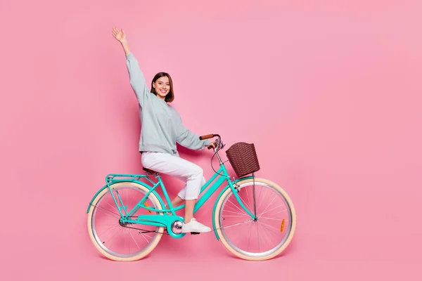 Full size profil boczne zdjęcie młodej dziewczyny fala hi jeździć rower weekend izolowany ponad różowy kolor tła — Zdjęcie stockowe