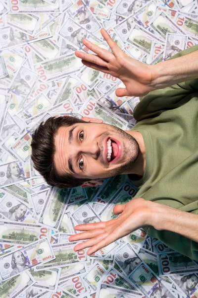 Alto ángulo de visión vertical retrato de hombre positivo impresionado levantar las manos aisladas en el fondo del dinero — Foto de Stock