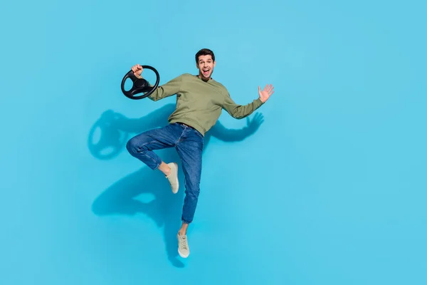 Foto de comprimento total de impressionado jovem morena cara dirigir carro salto desgaste camisa jeans tênis isolado no fundo azul — Fotografia de Stock