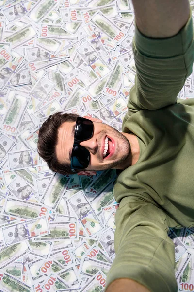 Arriba de la vista vertical de la persona alegre excitado tomar selfie yacía cashback aislado en el fondo del dinero — Foto de Stock