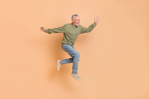 Pełny rozmiar zdjęcie chłodny starszy siwy hairdo człowiek biegać nosić pullover dżinsy buty izolowane na beżowym tle — Zdjęcie stockowe