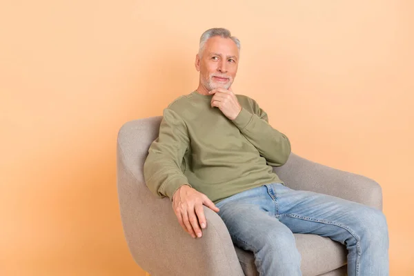 Foto de calma mais velho cinza penteado homem sentar olhar promo desgaste verde pulôver jeans isolado no fundo cor bege — Fotografia de Stock