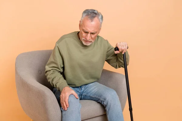 Foto do homem penteado cinza mais velho estressado sentar com vara desgaste pulôver jeans isolado no fundo bege — Fotografia de Stock