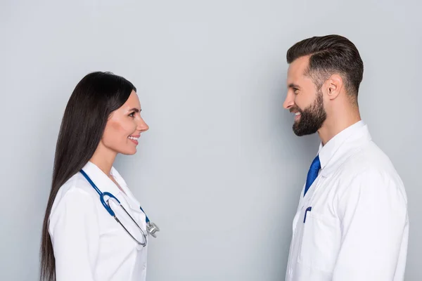 Foto de seguro positivo dos médicos usan abrigos blancos que se miran el uno al otro fondo de color gris aislado — Foto de Stock