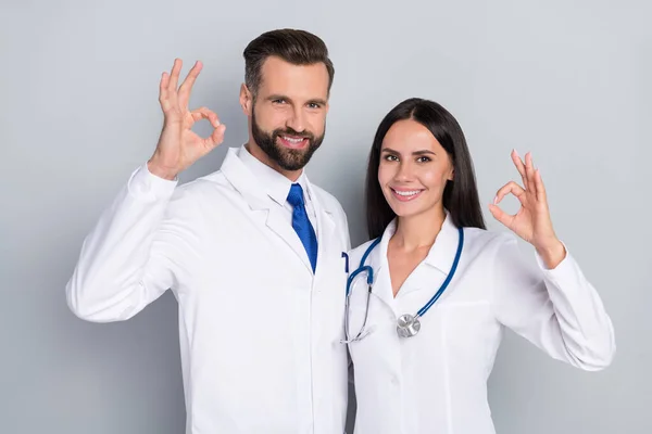 两名专业医生的画像显示，穿着灰色背景的白色外套是个很好的象征 — 图库照片