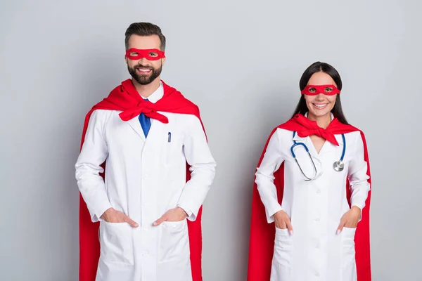 Portrét dvou atraktivních veselých sebevědomých doktorů terapeuti první pomoci super tým izolované přes šedé barvy pastelové pozadí — Stock fotografie