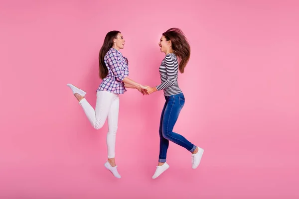 Profilo completo del corpo foto di due eccitate ragazze sportive tenere le braccia saltando isolato su sfondo di colore rosa — Foto Stock
