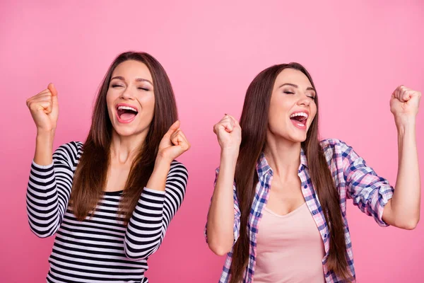 Photo de deux filles heureuses satisfaites les yeux fermés lever les poings crier oui isolé sur fond de couleur rose — Photo