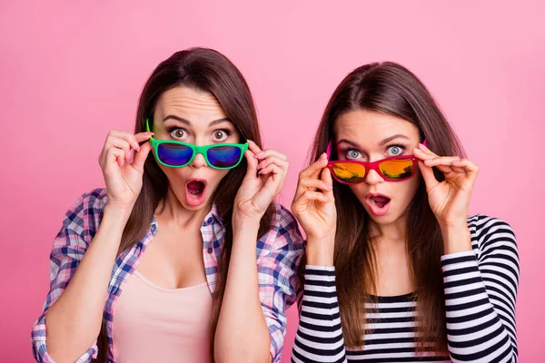 Portret dwóch pięknych dziewcząt dotykać okulary otwarte usta izolowane na różowy kolor tła — Zdjęcie stockowe