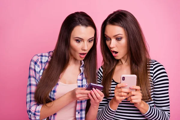 Foto de impresionados dos personas usan teléfono demuestran cada una de las noticias aisladas en el fondo de color rosa — Foto de Stock