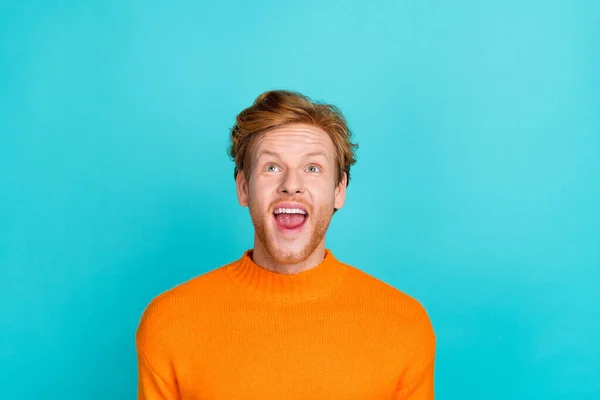 Foto van onder de indruk grappige man gekleed oranje trui open mond op zoek omhoog lege ruimte geïsoleerde turquoise kleur achtergrond — Stockfoto