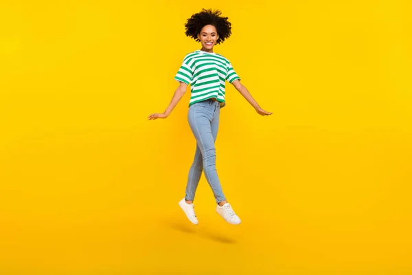 Full body photo of cute millennial lady jump wear t-shirt jeans shoes isolated on yellow background — Stock Photo, Image