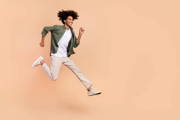 Longitud completa cuerpo tamaño vista de atractivo alegre energético chico saltando corriendo aislado sobre beige pastel color fondo — Foto de Stock