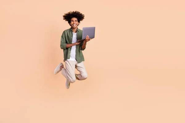 Plná délka fotografie vzrušený veselý pohledný muž držet bezdrátové netbook izolované na béžové barvy pozadí — Stock fotografie