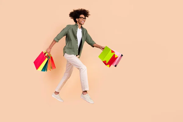 Full length profile portrait of active shopaholic hold packages look empty space isolated on beige color background — Stockfoto