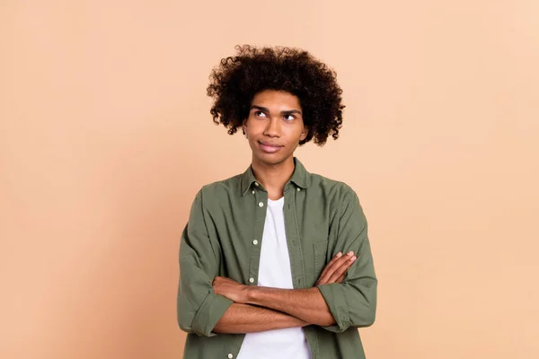 Portret van aantrekkelijke nieuwsgierige golvende man gevouwen armen overdenken kopieerruimte geïsoleerd over beige pastel kleur achtergrond — Stockfoto