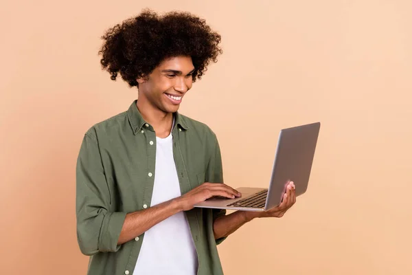 Portrét atraktivní veselý zkušený vlnitý chlap pomocí notebooku psaní e-mail izolované přes béžové pastelové barvy pozadí — Stock fotografie