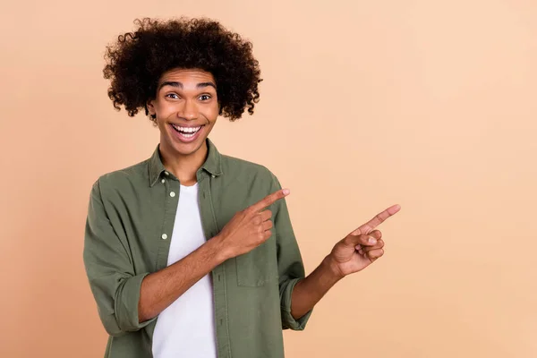 Portrait of attractive amazed cheerful wavy-haired guy demonstrating copy space new novelty isolated over beige pastel color background — Stock Photo, Image