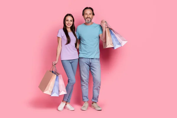 Foto de tamaño completo de dos compañeros agradables alegres abrazan paquetes de retención aislados en el fondo de color rosa — Foto de Stock