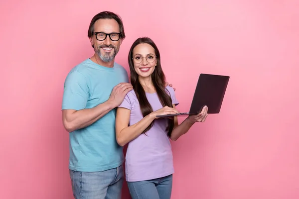 Portré két vidám barátságos partnerek ölelkezni tartsa használja vezeték nélküli netbook hálózatépítés elszigetelt rózsaszín színű háttér — Stock Fotó